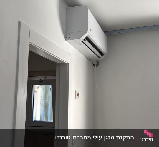 התקנת מזגן עילי לבן על קיר פנימי מעל פתח דלת